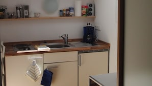 A compact kitchen with a skylight, wooden cabinets, a built-in oven, and a coffee maker. - Small apartment for a maximum of 2 people in a unique location directly on the lake (Rottach-Egern)