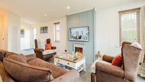 A living room with a fireplace, a television, and a dining table. - 1 bedroom accommodation in Holton Heath (Holton Heath)