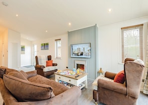 A living room with a fireplace, a television, and a dining table. - 2 bedroom accommodation in Holton Heath (Holton Heath)