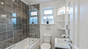 A modern bathroom with a bathtub, toilet, and sink. - 1 bedroom accommodation in Holton Heath (Holton Heath)
