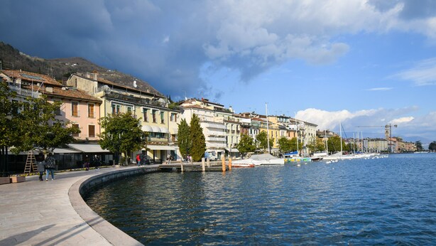Une promenade en bord de mer, bordée d’immeubles, avec un quai et des bateaux.