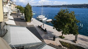 Une promenade en bord de mer, avec des bateaux amarrés, un ciel dégagé et des bâtiments qui bordent le rivage.