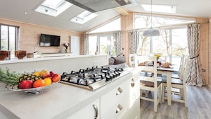 Une cuisine moderne équipée d’une cuisinière à gaz, d’un panier de fruits et d’un coin repas avec une table et des chaises.
