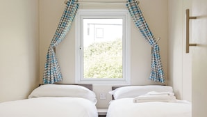 Ein Zimmer mit zwei Betten, einem Fenster und Vorhängen.
