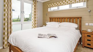 Een slaapkamer met een bed, een raam, een nachtkastje en een lamp.