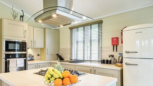 Een moderne keuken met een centraal eiland, roestvrijstalen apparatuur en een raam met zonwering.