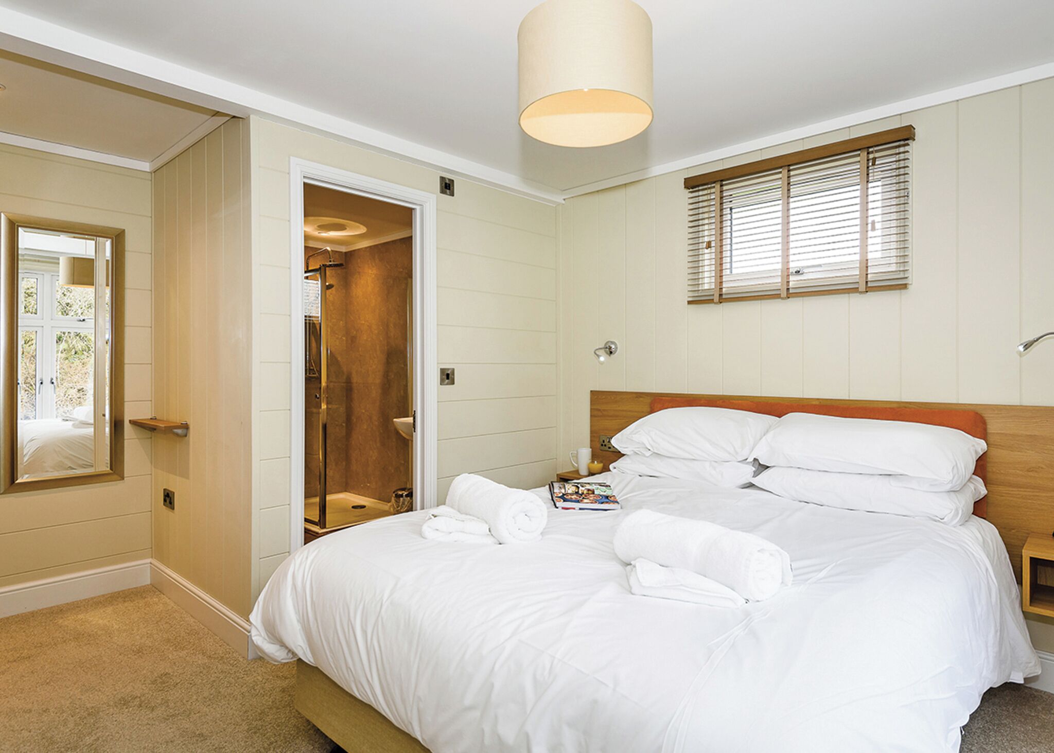 A bedroom with a bed, a mirror, a walk-in closet, and a window with blinds.