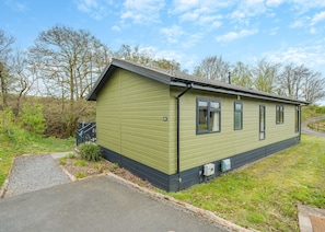 A single-story building with a green exterior, a small porch, and a paved driveway.