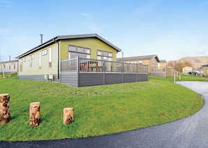 Une maison de plain-pied avec une terrasse entourée d’une clôture, une pelouse et une allée pavée.