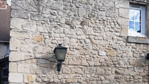 Un edificio de piedra con una pequeña entrada y una farola encima.