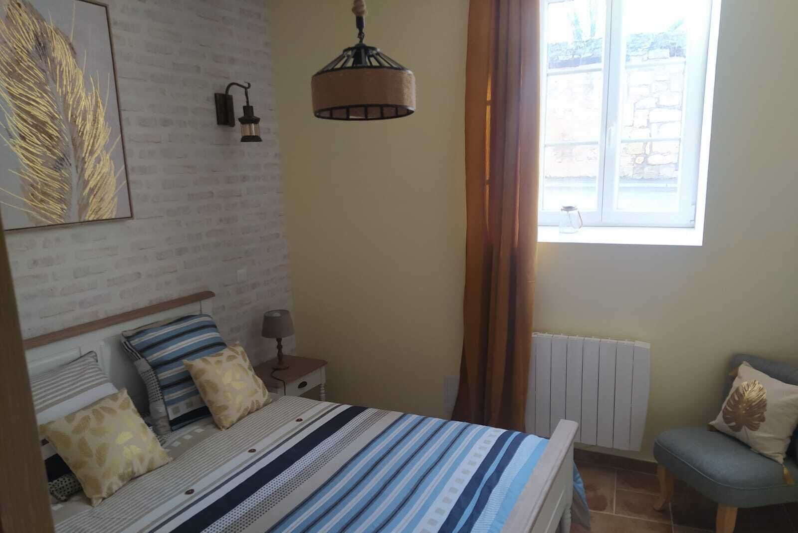 Une chambre à coucher avec un lit, une lampe de chevet et une fenêtre avec des rideaux.
