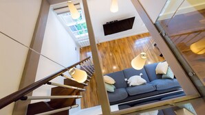 A modern interior with a staircase, a blue sofa, and pendant lights.