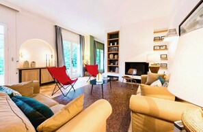 A modern living room with a sofa, red chairs, a coffee table, and a bookshelf.