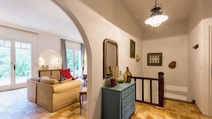 Ein Zimmer mit einer Couch, einem Schrank, einem Spiegel und einer Treppe.
