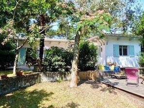A residential property with a patio, outdoor seating, and a white building with blue shutters.