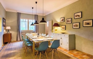 A dining area with a long table set for four, surrounded by chairs, with pendant lights above. - Holiday home with idyllic terrace on the bay A0372 (Cap Ferret)