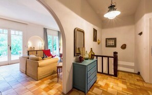 A room with a sofa, a dresser, a mirror, and a staircase.