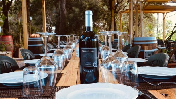 Une table mise pour un repas, avec des verres à vin, des assiettes et une bouteille de vin.