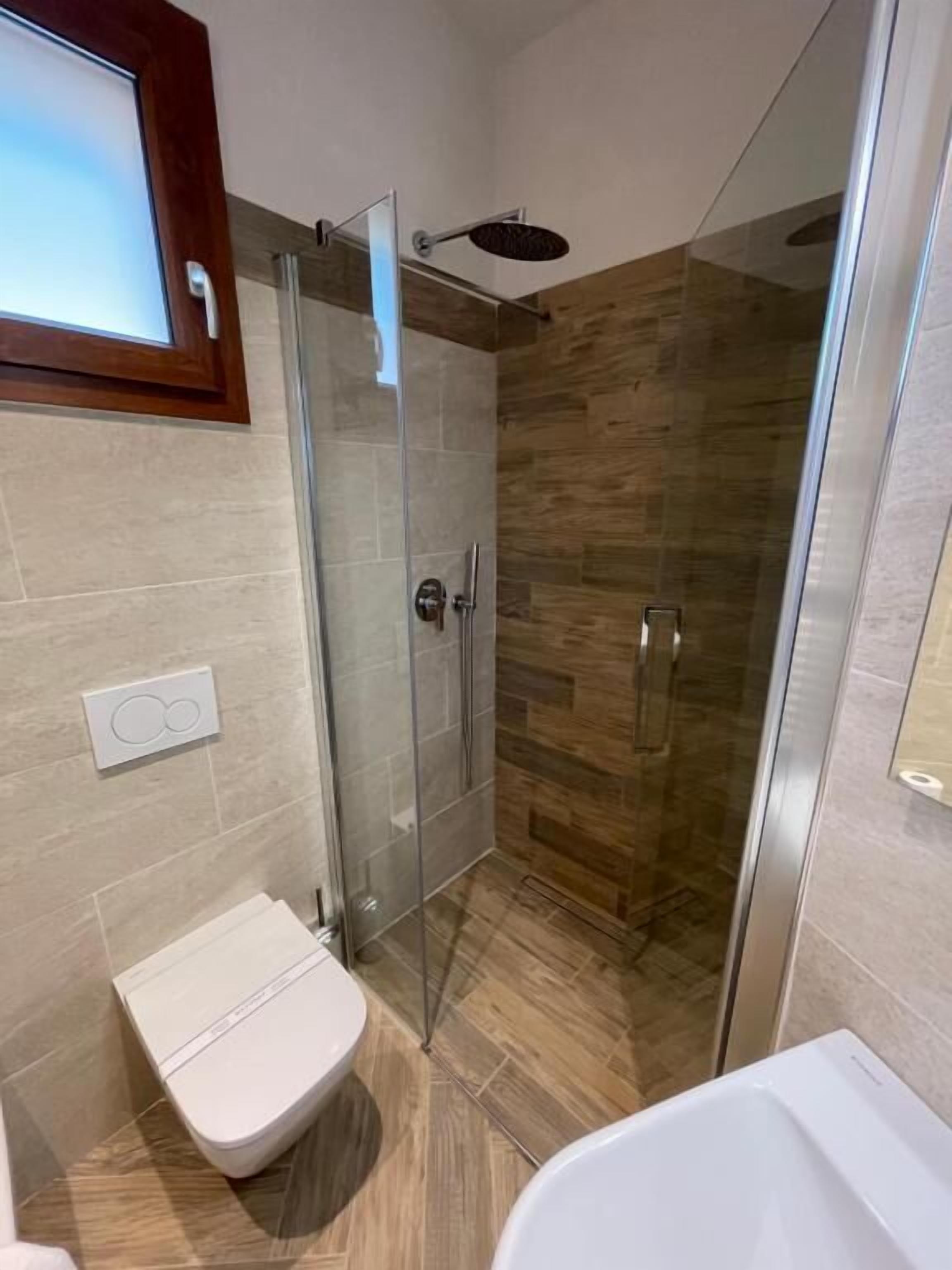 Une salle de bain moderne avec une douche à parois de verre, des toilettes et une baignoire.
