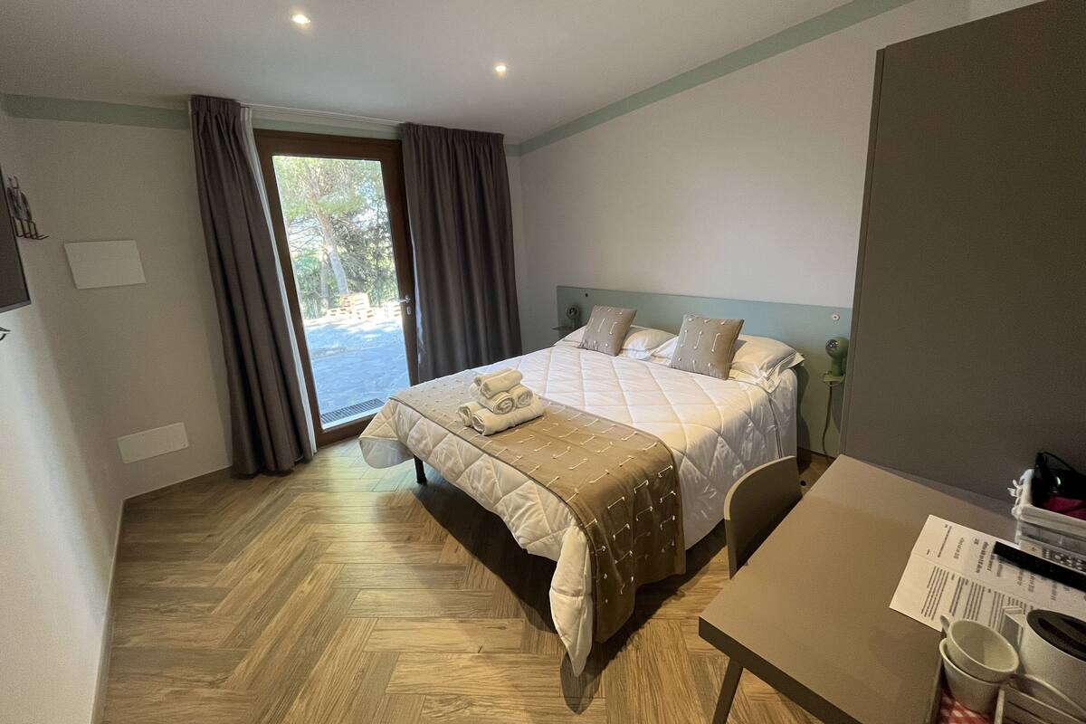 Una habitación de hotel con cama, escritorio y vista al exterior.