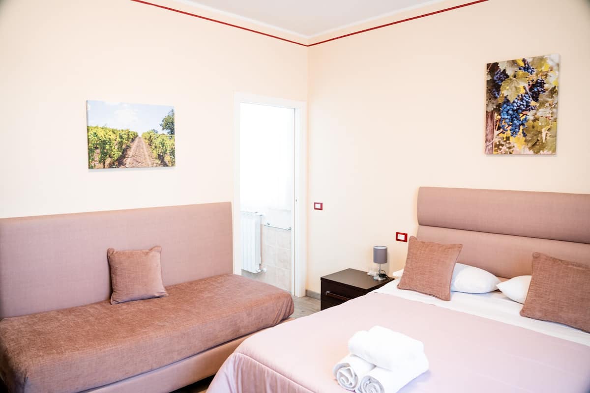 Una habitación de hotel con una cama, un sofá y dos cuadros en las paredes.