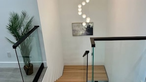 Een moderne trap met glazen leuningen, een houten afwerking en een rij bolvormige lampjes.