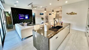 Een moderne keuken met een marmeren eiland, witte kasten en hanglampen.