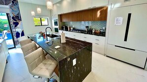 Een moderne keuken met een centraal eiland, witte kastjes en uitzicht op de omgeving.