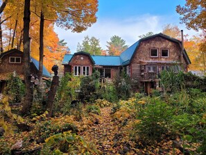 A rustic cabin-style hotel with multiple wooden buildings, surrounded by autumn foliage and a garden. - MY STRUGGLE: The authentic cabin experience—a simple place to come together! (Saint-Michel-de-Bellechasse)