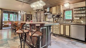 A spacious kitchen with a large island, wooden bar stools, and a chandelier. - MA GALÈRE, Eco-responsible house by the river. (Saint-Michel-de-Bellechasse)