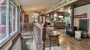 A cozy interior with a wooden staircase, a dining area, and a kitchen with a stove. - MA GALÈRE, Eco-responsible house by the river. (Saint-Michel-de-Bellechasse)