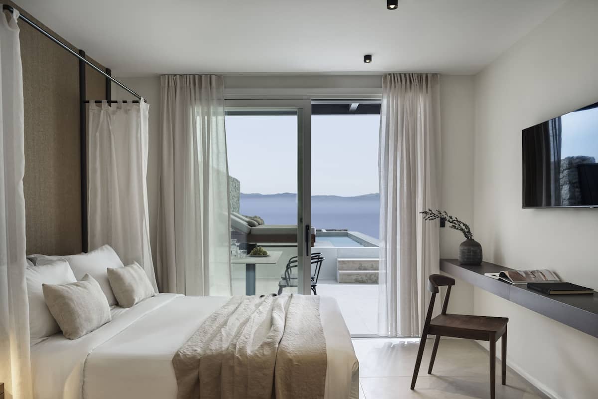 Une chambre d’hôtel moderne équipée d’un grand lit, d’un bureau, d’une chaise et d’un téléviseur.