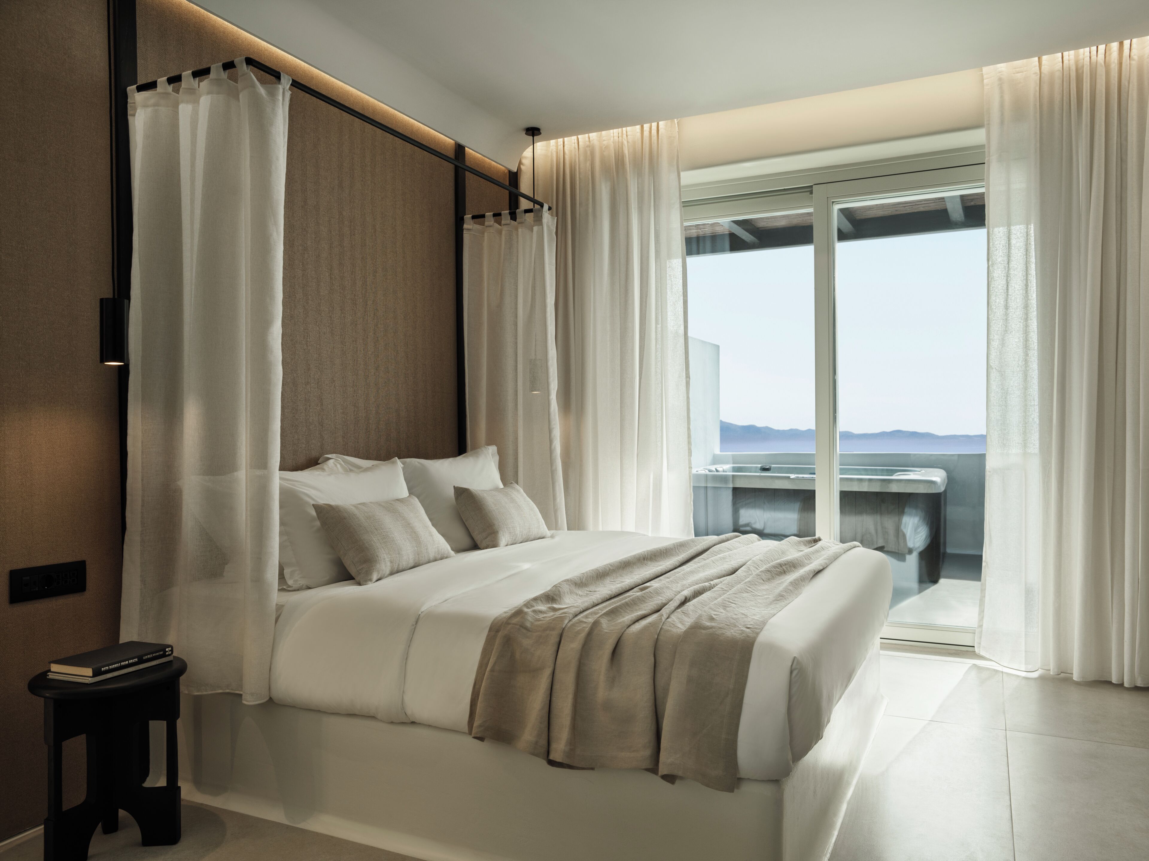 Une chambre moderne avec un grand lit, une vue sur la mer et un balcon équipé d’un évier.