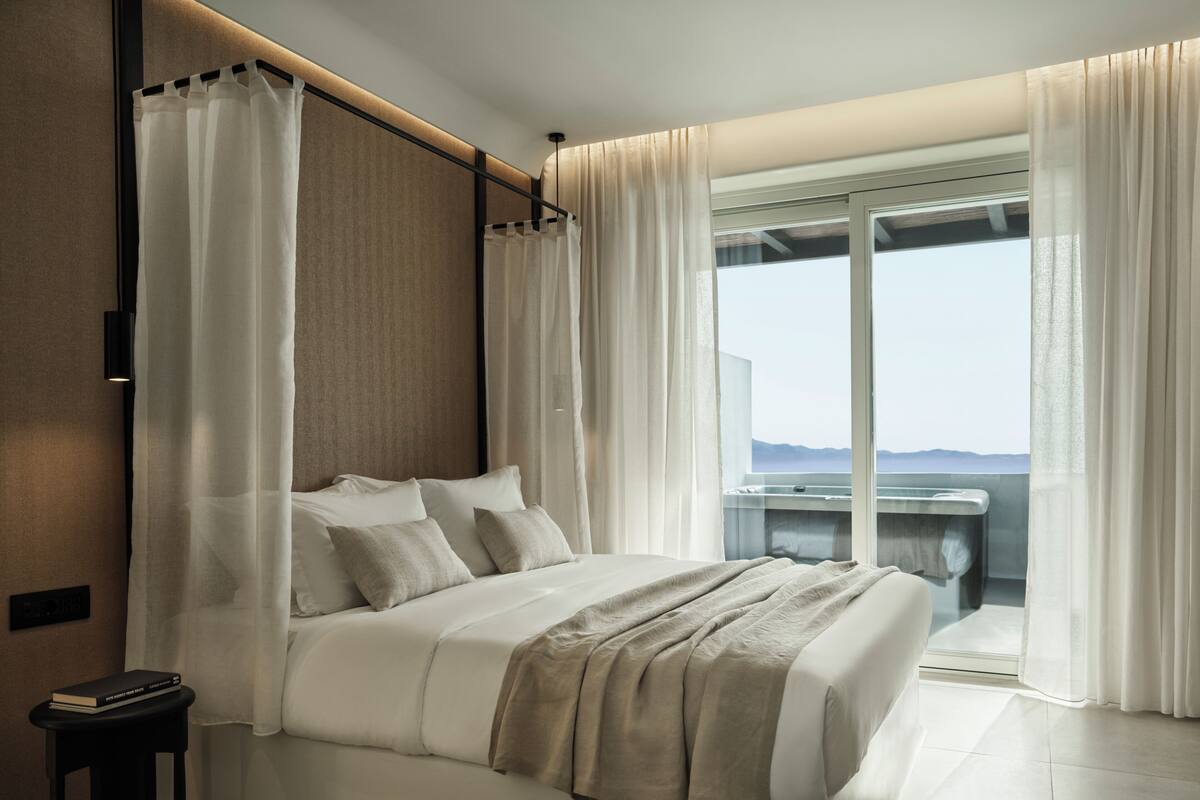 Une chambre moderne avec un grand lit, une vue sur la mer et un balcon équipé d’un évier.