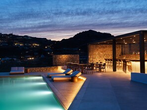 A rooftop pool area with lounge chairs and a bar.