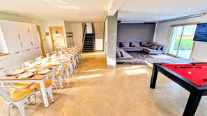 A modern interior with a dining area, a pool table, and a living room with a sofa and a view through a glass door. - Architect house / Heated swimming pool all year / Billiards / Table football (Magnien)