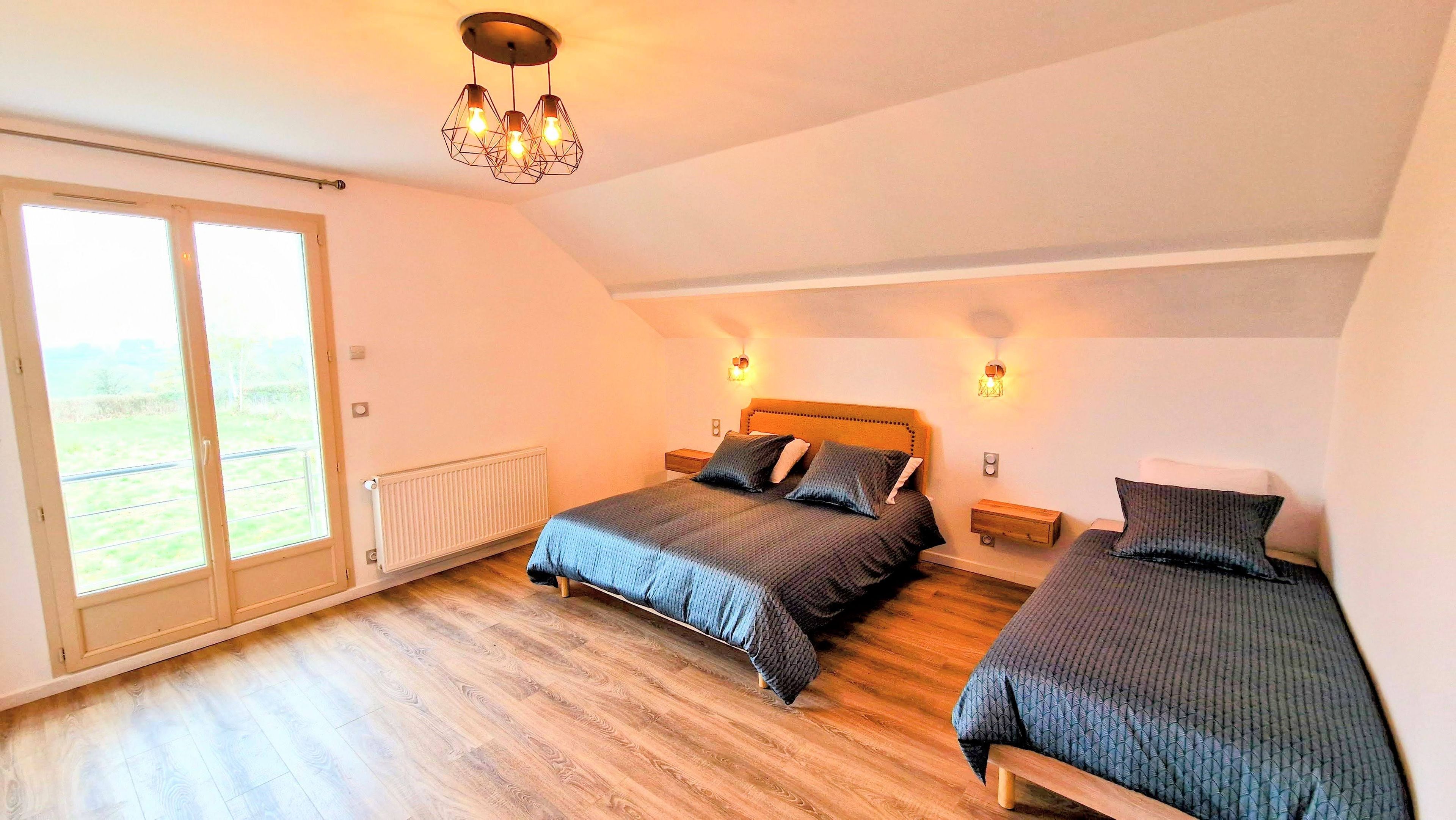 Une chambre avec deux lits, un radiateur, une fenêtre et un luminaire au plafond.