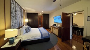 Ein Hotelzimmer mit Bett, Schreibtisch, Fernseher und Deckenventilator.