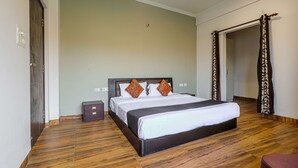 A bedroom with a large bed, wooden flooring, and a door leading to another room. - IVA 1 BHK - w/ Wi-Fi, Kitchen, Food, Balcony, Garden (Sukha)