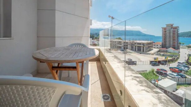 Un balcón con una mesa y sillas, con vistas a un paisaje urbano con edificios y cielo despejado.