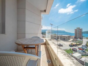 A balcony with a table and chairs, overlooking a cityscape with buildings and a clear sky. - Seaside Rest Apartments (Budva)