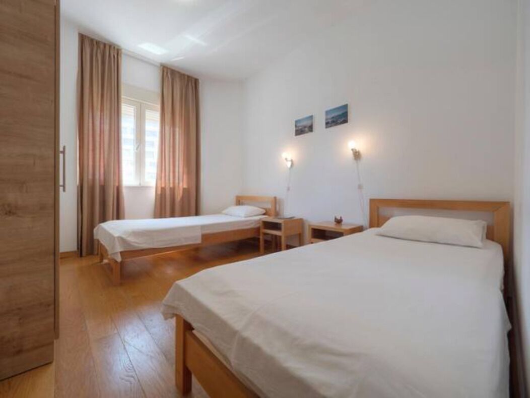 A room with two single beds, a wooden wardrobe, a desk, and a window with curtains.