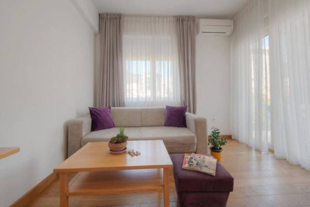 A modern living room with a sofa, a wooden coffee table, and a small table with a plant.