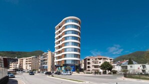 Un hotel de varios pisos con fachada curva, situado en un pueblo bajo un cielo azul despejado.