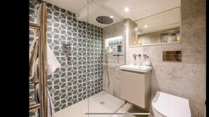Et badeværelse med tapet på væggen, en bruser, en vask og et toilet.