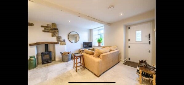 A cozy living room with a beige sofa, a wooden coffee table, a fireplace, and a television.