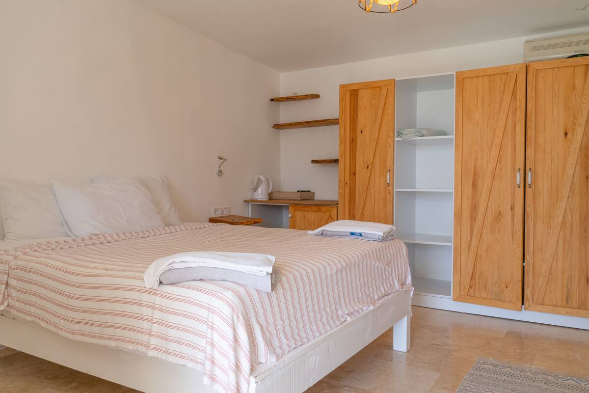 Un dormitorio con cama, armario de madera, estanterías y mesita de noche.
