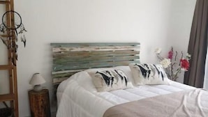 A bedroom with a bed, a wooden ladder, a small table with a lamp, and a wall-mounted dreamcatcher. - Gîte ave Piscine (Illats)