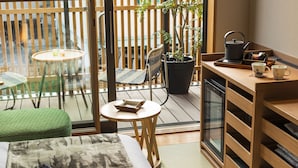 A compact room with a bed, a small round table, a chair, a sofa, a wooden desk, a kettle, and a potted plant. - onomichi-hansei (Onomichi)