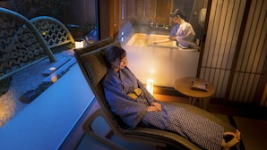 A person relaxing in a sun lounger with a view of a traditional Japanese room, including tatami flooring and a sliding door. - onomichi-hansei (Onomichi)